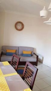a living room with a couch and a clock on the wall at Appart'hotel Les Capucins in Mahajanga