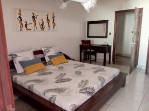 a bedroom with a bed with a desk and a table at Appart'hotel Les Capucins in Mahajanga