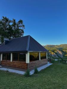 a house with a black roof on a grass field at Villa Vasilije in Šavnik