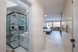 a bathroom with a glass shower and a living room at Mirage Bay Deluxe in Sarandë +172 photos