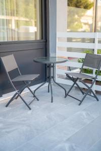 a glass table and two chairs on a patio at DNS Elements Apartments 2 in Nea Karvali