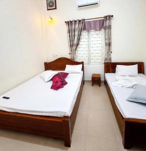 two twin beds in a room with a window at Long Khang Hotel in Quang Tri