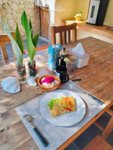 a table with a slice of pizza on a plate at Oemau Bungalow in Nembrala +19 photos