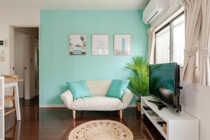 a living room with a white chair and a television at MARSEA Resort in Zushi