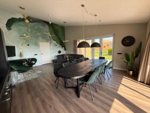 a dining room with a table and green chairs at Beach House 314 in Hindeloopen