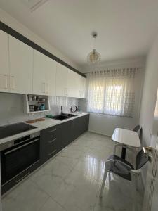 a kitchen with white cabinets and a table and a chair at Prive Home in Maliq