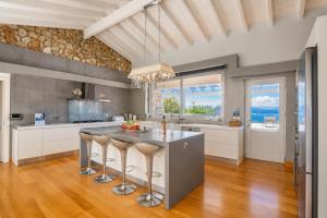 a kitchen with a large island with bar stools at Villa Helios Corfu Kassiopi in Kassiopi