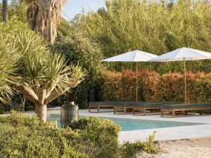 two benches and umbrellas next to a swimming pool at Casa da Ria in Tavira +31 photos