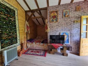 a room with a bed and a tv on a brick wall at La căsuța din poveste in Pătîrlagele
