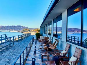 a balcony with chairs and tables and a view of the water at さざね in Kyonan