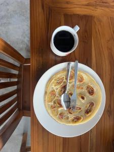 a plate with a fork and a cup of coffee at SleepHere Homestay in Bayan +14 photos