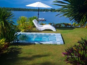 a pool with a white chair and an umbrella at The Clifftop Home in Esperanza