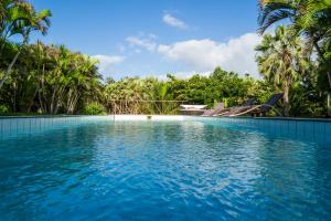 a swimming pool with blue water and palm trees at Refúgios Parajuru - Villa Cristiano in Parajuru