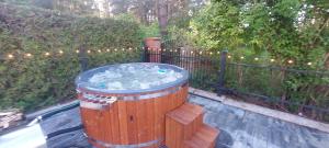 a hot tub in a wooden barrel in front of a fence at Apartament AURA - Cichy Zakątek - Kujanki in Kujanki