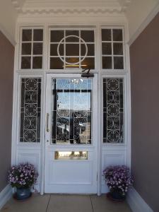 a white door with windows and two vases with purple flowers at Palace Hotel - Small Hotel in Oban