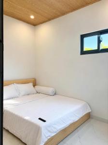 a bedroom with a bed with white walls and a window at Phước Hải Đẹp Homestay in Chợ Phước Hải