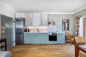a kitchen with blue cabinets and a refrigerator at Hof am Ammersee in Pähl