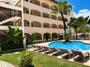a resort with a swimming pool and chairs and a building at Hosts BR - La Serena Suíte Cumbuco in Caucaia