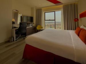 a hotel room with a large bed and a window at Carnelian Muscat - Airport Hotel in Muscat +32 photos
