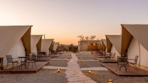 a row of tables and chairs with candles on a road at Jacob Mitzpe Ramon in Mitzpe Ramon +25 photos