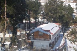 an aerial view of a house with snow on the roof at Royal Dutch Resorts and Doll Museum in Mukteswar