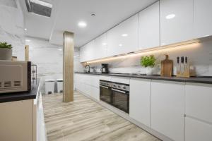 a white kitchen with white cabinets and a microwave at Rialto Millau Coliving in Villaviciosa de Odón