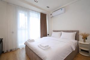 a bedroom with a large white bed with two towels on it at Chic city apartment I By Domel Yerevan in Yerevan