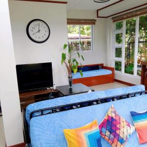 a living room with a blue couch and a clock at KRUEGERs Cottage in Sipalay