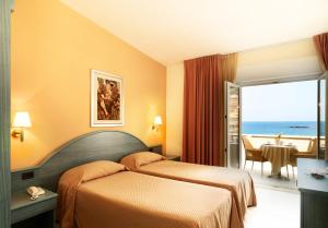 a hotel room with two beds and a balcony at Hotel & SPA Riviera Castelsardo in Castelsardo
