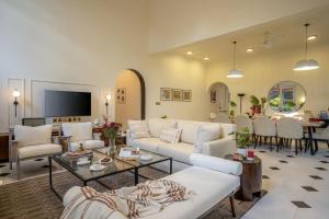 a living room with white couches and a dining room at Villa Kefi in Assagao