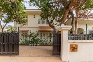 a white house with a black gate and trees at Villa Kefi in Assagao