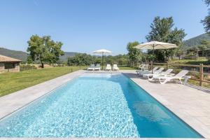 a swimming pool with lounge chairs and umbrellas at Mas Ca la Rossa in Girona