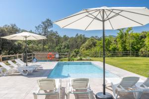 a swimming pool with chairs and an umbrella and a pool at Mas Ca la Rossa in Girona
