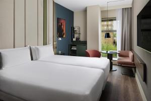 a hotel room with a white bed and a chair at NH Barcelona Diagonal Poblenou in Barcelona