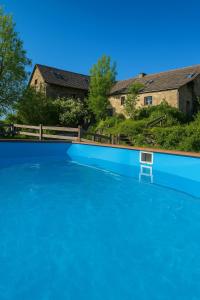 a large pool of blue water in front of a house at Saisonnée - Gîtes de Charme en Aveyron in Centrès