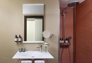 a bathroom with a sink and a mirror and a shower at NH Barcelona Diagonal Poblenou in Barcelona