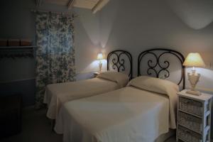 two beds in a bedroom with two lamps on at Agriturismo La Dondina in Budrio