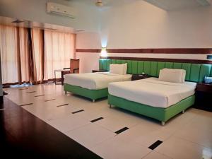 a hotel room with two beds and a table at The Sea Princess Hotel in Cox's Bazar