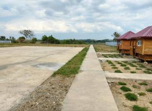 a field with two wooden buildings and a road at Villa Cedes in Lasam