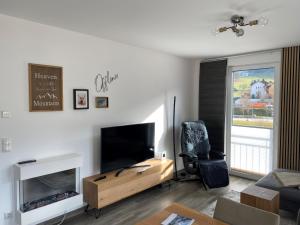 a living room with a flat screen tv and a chair at Ferienwohnung Klugis in Gosau +6 photos