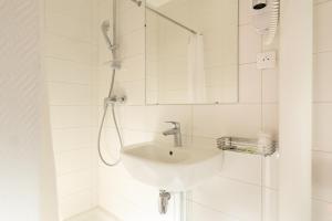 a white bathroom with a sink and a shower at Hôtel Saint Roch in Paris +20 photos