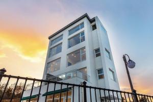a tall white building with a sunset in the background at Donghae aeodalari pension in Donghae