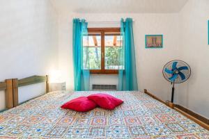 a bedroom with a bed with two red pillows on it at Villetta Pineta in Santa Margherita di Pula