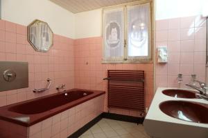 a pink bathroom with a tub and two sinks at Gemütliches Appartement im Emmental - Sumiswald in Sumiswald +8 photos