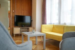 a living room with a yellow couch and a tv at Gemütliches Appartement im Emmental - Sumiswald in Sumiswald