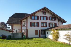 a large white house with red windows and a yard at Gemütliches Appartement im Emmental - Sumiswald in Sumiswald