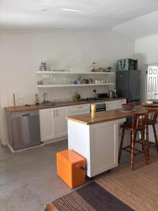 a kitchen with white cabinets and a table and chairs at Bayerley in Plettenberg Bay
