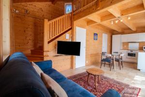 a living room with a blue couch and a kitchen at Chalet des Épicéas in Chorges