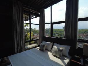 a bedroom with a bed and a large window at Ohmmstay - Rumah Pendopo in Tanjungtirto
