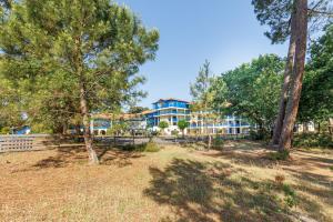 a park with trees and a building in the background at La Canopée - Conciergerieland in Soustons